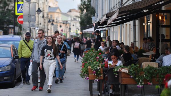 Прохожие идут мимо летней веранды кафе в Москве