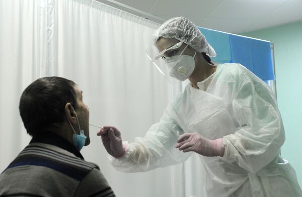 Медицинская сестра берет мазок у пациента для ПЦР-теста на коронавирус COVID-19