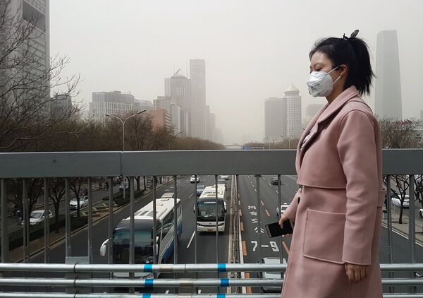 Жительница Пекина в защитной маске во время смога