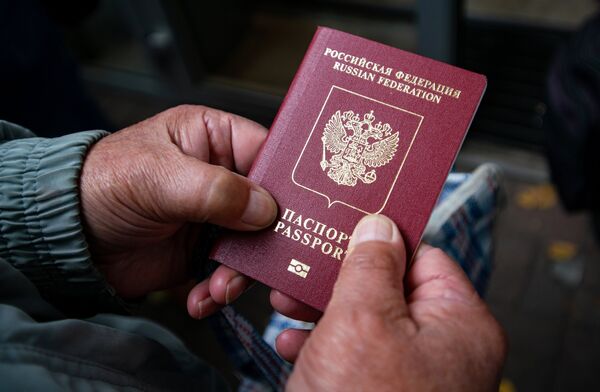 Мужчина держит в руках свой паспорт в день выборов депутатов Государственной Думы РФ