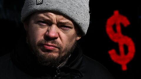 Мужчина проходит мимо пункта обмена валют со знаком доллара