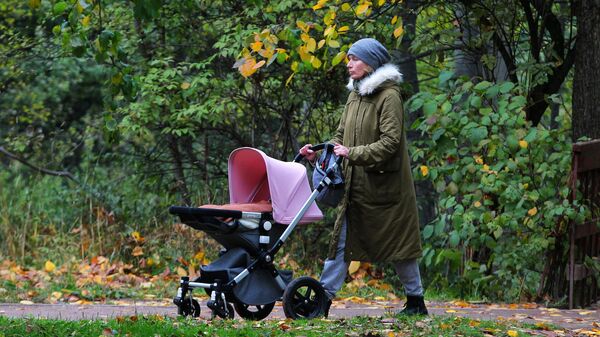 Женщина с детской коляской гуляет в музее-заповеднике Коломенское в Москве