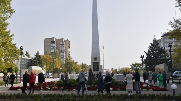 Люди возле стелы Мелитополь - город воинской славы на площади Победы в Мелитополе