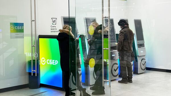 Люди у банкоматов в отделении Сбербанка в Москве